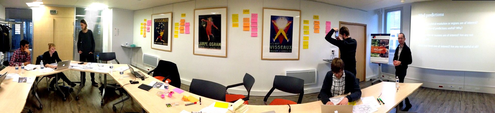 User workshop with domain experts around meeting tables, sticky notes and vintage electricity posters on the wall
